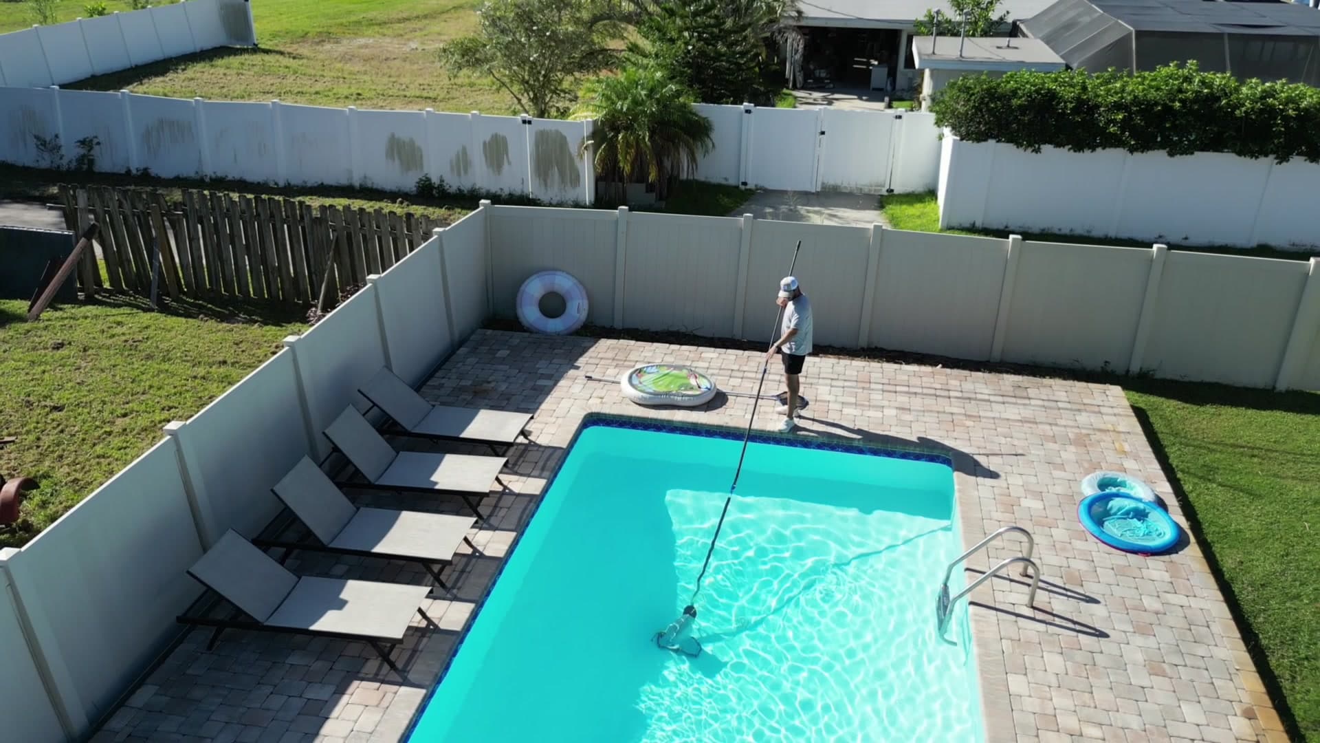 Top-down view of a turquoise pool being skimmed